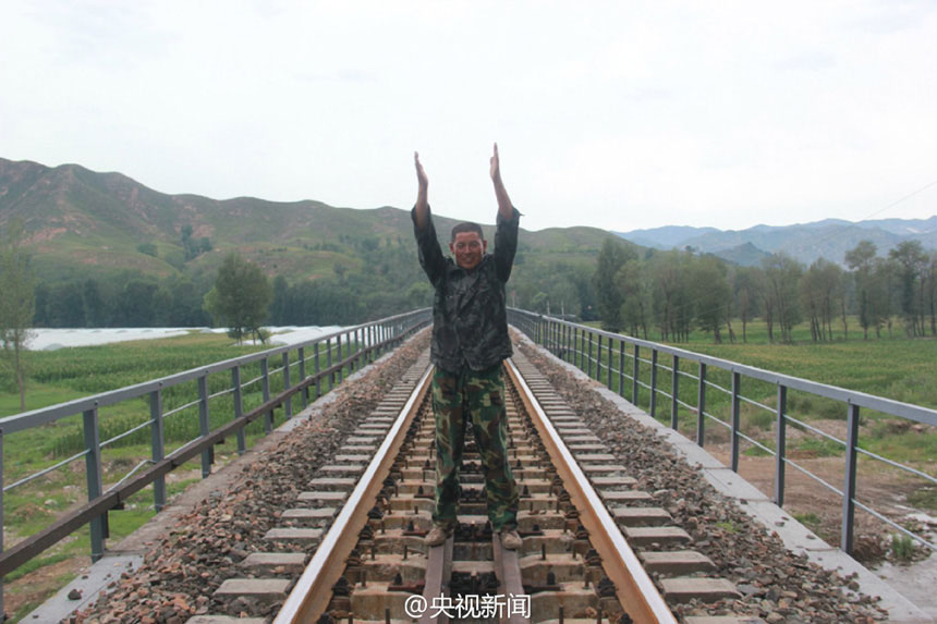 صورة: يعيد لو وي صورة إشارته لإيقاف القطار وهو واقف في منتصف المسارات.