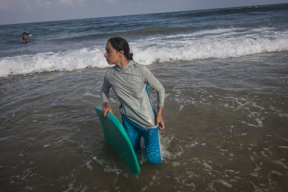الفتاة غانمة البالغة من العمر 14 عاما تلعب ركوب الأمواج خارج مدينة غزة. 