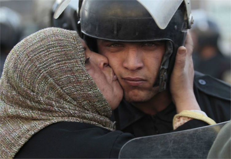 8. امرأة مصرية تقبل رجل شرطة الذي رفض إطلاق النار على المدنيين المحتجين في الشوارع