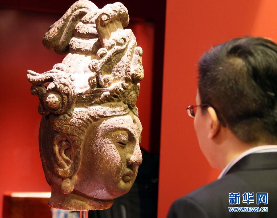 زائر يشاهد تمثالا بوذيا من الصين القديمة في المعرض التحضيري للمزاد العلني في 28 مايو الجاري.