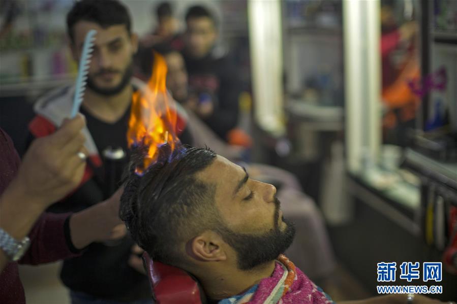 حلاق فلسطيني يستخدم النار في حلاقة الشعر في مخيم رفح في قطاع غزة