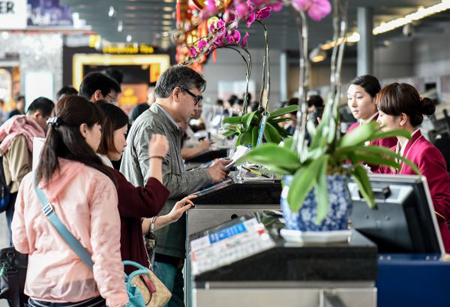 المسافرون الصينيون يقومون بتسجيل الخروج في نقطة المغادرة الدولية بالمطار  