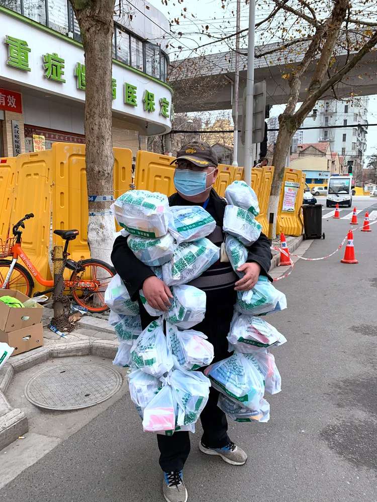 صورة مؤثرة: عامل حي سكني بووهان مغطى بأكياس الدواء