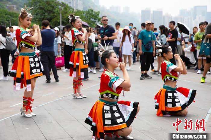  رقص فتيات قومية مياو على جانب مبنى يمر وسطه قطار تشونغتشينغ الأحادي يجذب أنظار المارة
