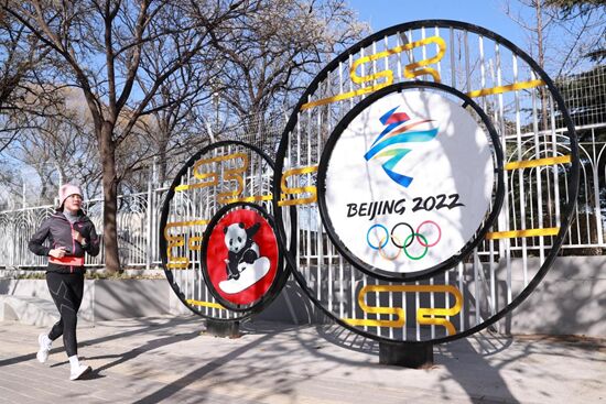 يوم 24 نوفمبر 2021، أحد عشاق الجري تمر من أمام لافتة لدورة الألعاب الأولمبية الشتوية لعام 2022 ذات الخصائص الصينية على طريق أوتي الأوسط، بكين. تشن شياوقن/ صورة الشعب
