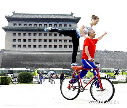 مسن صيني وفتاة المانية في استعراض مشترك لمهارة ركوب الدراجة 