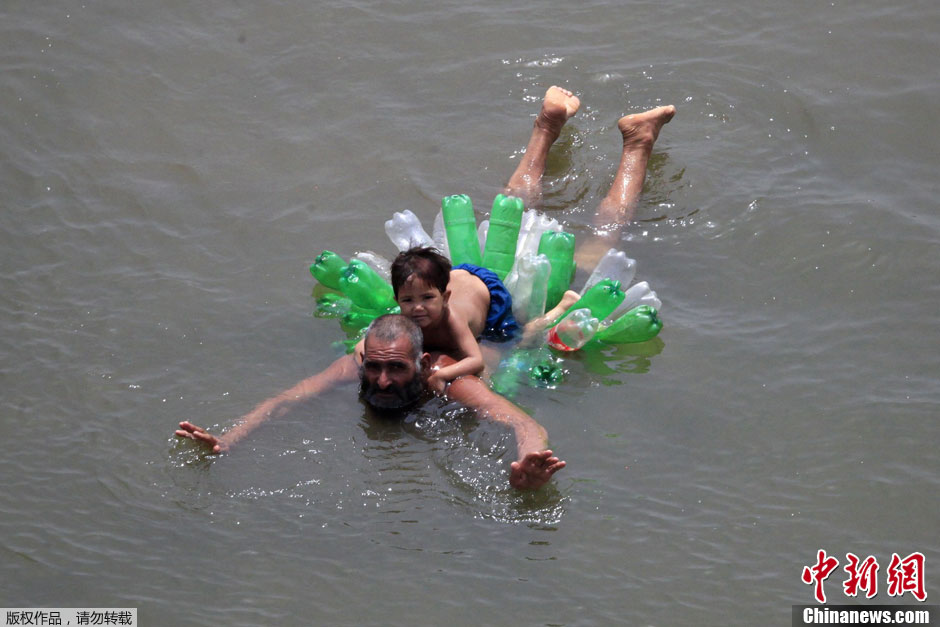 باكستاني يسبح مع ابنته في نهر رافي باستخدام زجاجات بلاستيكية فارغة بضاحية مدينة لاهور الباكستانية في 26 يوليو 2012