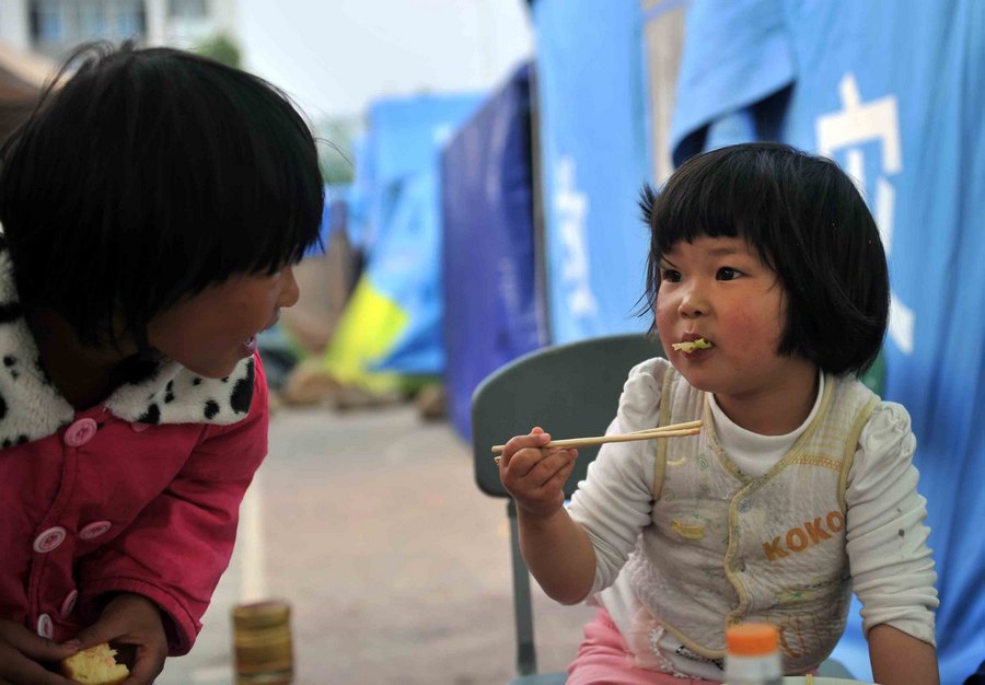 طفلة تتناول الفطور خارج خيمة بمأوى مواطنين منكوبين في مدرسة لوشان الثانوية صباح يوم 26 إبريل الجاري.