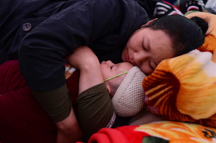 أم تحضن طفلها أثناء النوم بمأوى مؤقت لمواطنين منكوبين في محافظة لوشان يوم 21 إبريل الجاري.