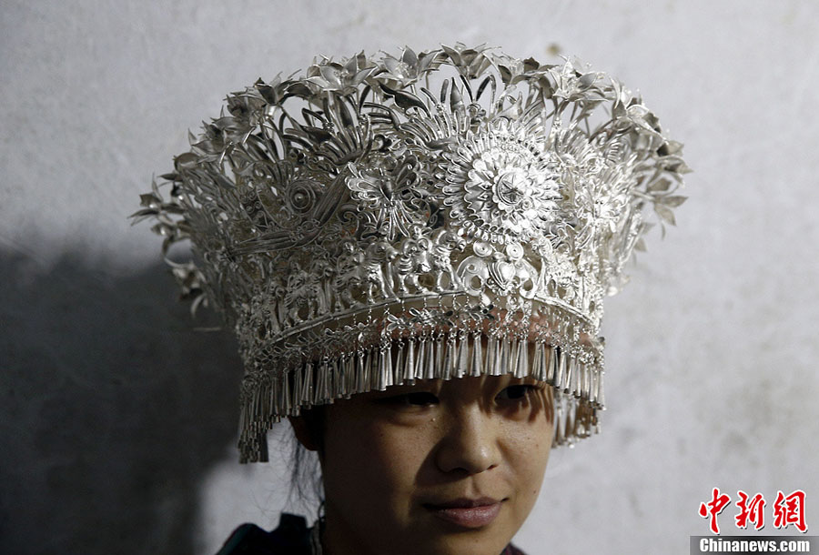 فتاة قومية مياو تعرض غطاء الرأس الفضي الصافي الذي صنعه يانغ قوانغ بين. 