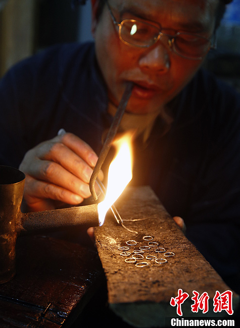 عامل يانغ قوانغ بين يصنع الحلق الفضية باستخدام فن اللحام.  