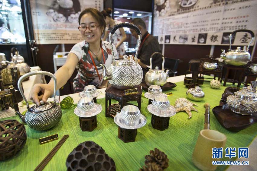 تظهر في هذه الصورة فتاة صينية وهي تعرض طقم الشاي الفضي الصافي والمصنوع يدويا في معرض بكين للعلامات التجارية الفاخرة لعام 2013 في يوم 22 يونيو الحالي.      
