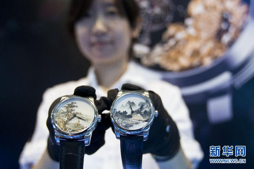 تظهر في هذه الصورة فتاة صينية وهي تعرض الساعة الفاخرة التي تم صنعها باستخدام فن الرسم الداخلي الصيني التقليدي في معرض بكين الدولي للعلامات التجارية الفاخرة لعام 2013 في يوم 22 يونيو الحالي.    