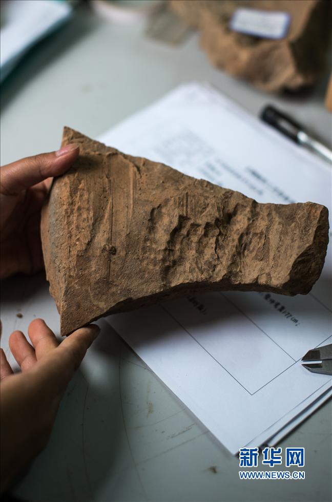 عامل في مختبر ترميم التحف الأثرية لمتحف ضريح تشين شي هوان يعرض السطح الداخلي من القطعة المحطمة في يوم 18 يوليو، فإن بصمات يد الحرفي واضحة.   