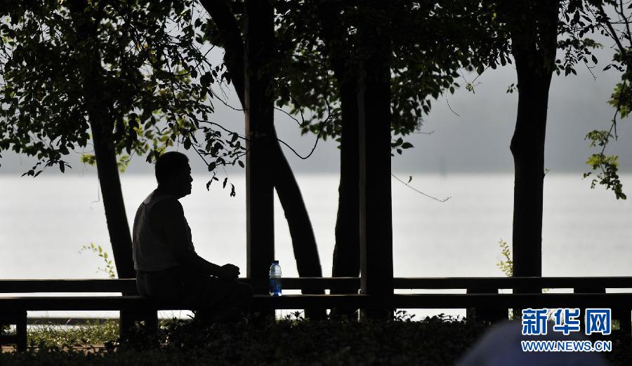 مواطن من ناجينغ يجلس تحت كشك في حديقة بحيرة  شوانوو للاحتماء من آشعة الشمس في يوم 29 يوليو الحالي.