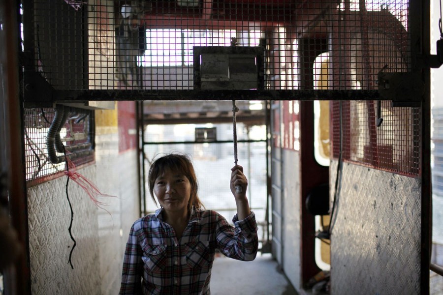 العاملة تسوه شياو هونغ تغلق باب المصعد  في موقع العمل. 