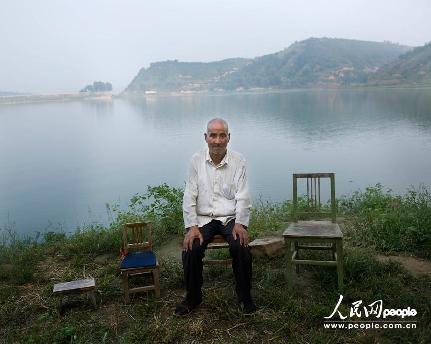 جياو شيوان تشنغ، البالغ من العمر 66 عاما يجلس على ضفة بحيرة قريبة من بيته الواقع في بلدة لينقاو بمحافظة بايشوي لمقاطعة شنشي(التقطت الصورة في يوم 27 أغسطس من عام 2011). وقد هاجر أولاده الثلاثة إلى المدينة للعمل.  