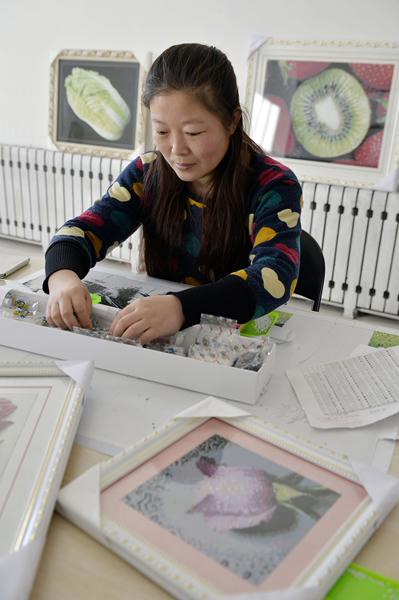جيانغ لي جيوان المعوقة سمعياً تبدع رسماً في مكتبها الفني